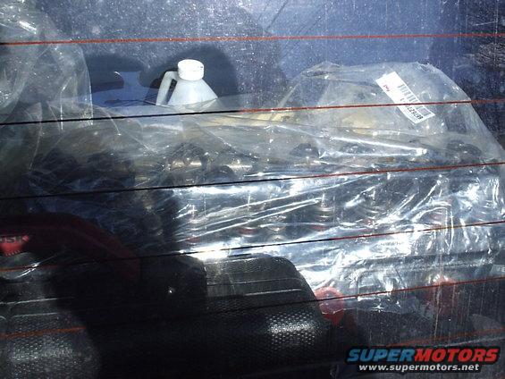 Plastic-wrapped parts and a white bottle on the back seat of a vehicle