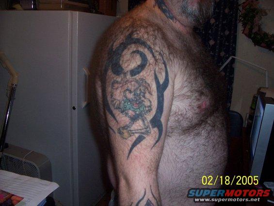 Tattoo on man's arm with tribal designs and a cartoon character