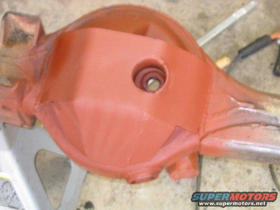 Differential housing painted orange, resting on a jack stand