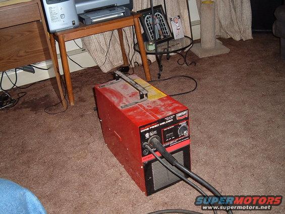Red wire feed welder with control knobs and cables