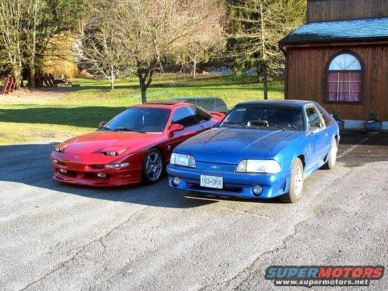 Red 1994 Ford Probe and blue Ford Mustang parked on asphalt