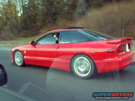 Red 1994 Ford Probe driving on a road, seen from another car