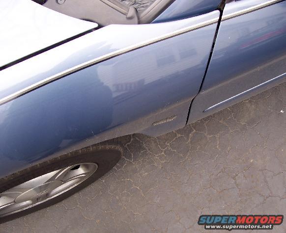Blue 1999 Ford Taurus side panel with chrome trim and alloy wheel