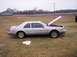 1992 Lincoln Mark VII - A silver coupe with its hood open sits in a field next to a building.