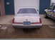 1992 Lincoln Mark VII - A 1992 Lincoln Mark VII is parked in front of a garage, with a service truck to its right.
