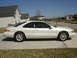 1997 Lincoln Mark VIII - A white 1997 Lincoln Mark VIII coupe is shown from the side, parked in front of a suburban house.