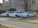 1997 Lincoln Mark VIII - Three white Lincoln vehicles are parked in front of a house. The vehicle on the right appears to be a Lincoln Mark VIII.