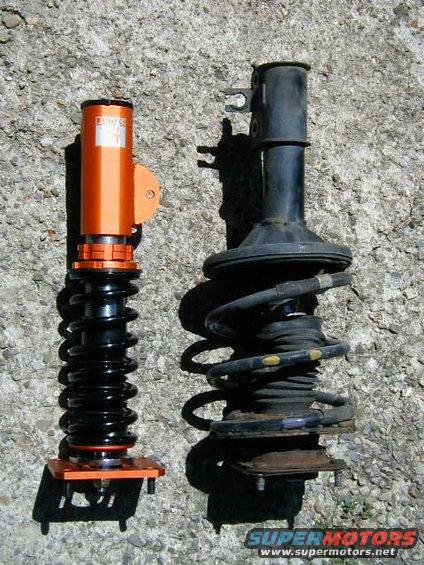 Orange aftermarket coilover next to a black stock strut assembly
