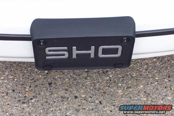 Close-up of a black car part with silver 'SHO' lettering