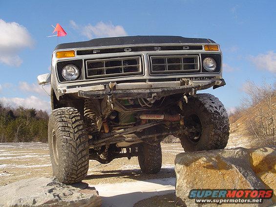 White 1978 Ford Bronco front view, lifted and off-roading over rocks