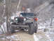 1979 Ford Bronco - A camouflaged Jeep CJ-5 navigates a snowy, off-road trail during winter.