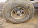 1979 Ford Bronco - Muddy off-road tire and wheel stuck in mud.