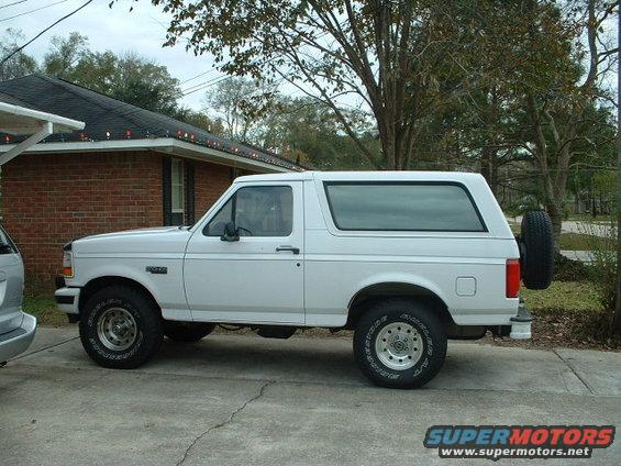 White 1996 Ford Bronco SUV parked on concrete driveway, side view