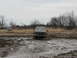 1985 Ford Bronco - Two off-road vehicles navigate a muddy terrain under an overcast sky.