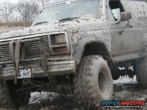Mud-covered SUV with a brush guard and large tires, angled from the front