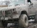1985 Ford Bronco - This SUV is heavily covered in mud, obscuring many details but its body style suggests an older model.