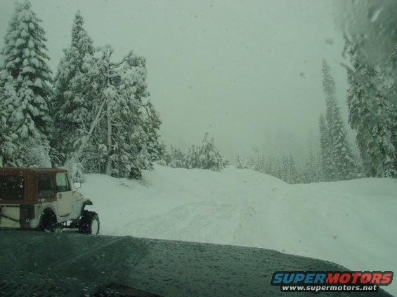 White and brown Jeep CJ-7 with tan soft top in snowy landscape