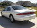 1997 Lincoln Mark VIII - Rear view of a white 1997 Lincoln Mark VIII parked on a concrete driveway with houses in the background.