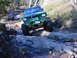 1990 Ford Bronco - Multiple off-road vehicles tackle a challenging rocky terrain on a wooded trail.