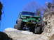 1990 Ford Bronco - This heavily modified SUV navigates a challenging rocky terrain under a clear blue sky.