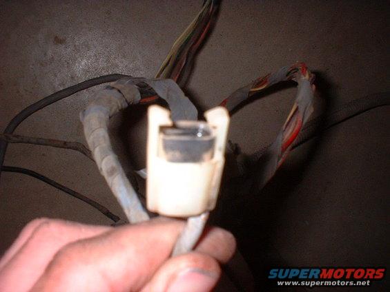 Hand holding a white electrical connector with a bundle of wires
