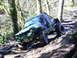 1990 Ford Bronco - Off-road vehicle navigating a muddy, wooded trail, with one wheel high off the ground.