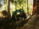 1990 Ford Bronco - A modified off-road vehicle tackles a challenging, uneven terrain in a forest setting.