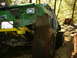 1990 Ford Bronco - A heavily modified green off-road vehicle navigates a muddy trail in a wooded area.