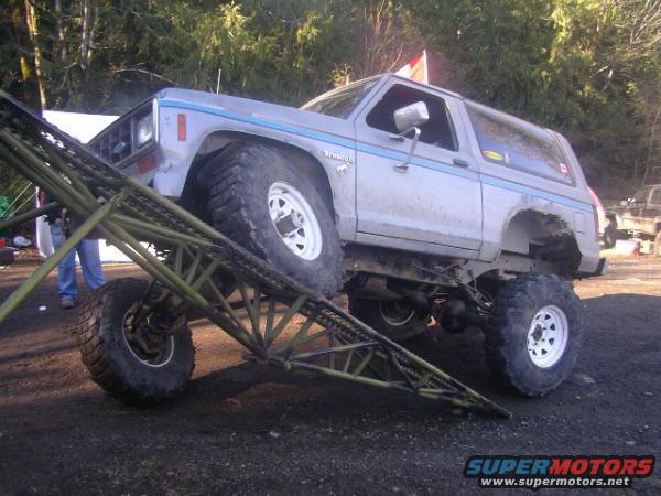 1984 Ford Bronco II with large tires on a metal ramp, another truck visible in background