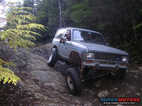 Silver 1984 Ford Bronco II off-roading on a rocky trail, front 3/4 view