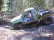 1990 Ford Bronco - A modified off-road vehicle navigates a muddy trail in a wooded area.