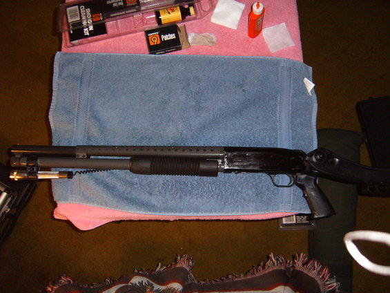 Shotgun laid out on towels with cleaning kit and patches nearby