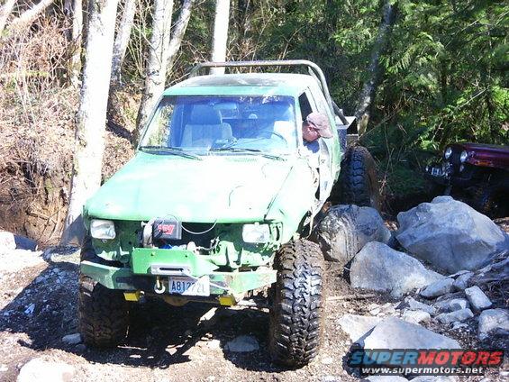 Green off-road vehicle with winch and license plate A81272L navigating rocky terrain