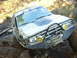 1990 Ford Bronco - An off-road vehicle navigates a muddy terrain, equipped with a winch and auxiliary lights.