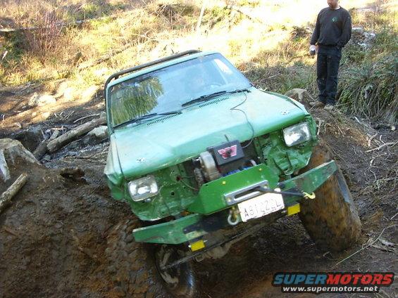 Green off-road vehicle with winch stuck in mud, front view