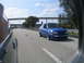 1998 Volkswagen Jetta - A blue hatchback is captured driving on a highway under a cloudy sky.