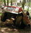 1975 Ford Bronco - An ATV sits in the woods, its orange and white body visible amongst the trees and leaves.