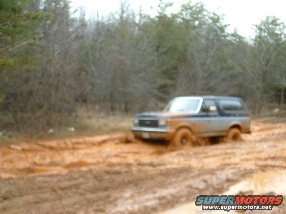 Mud-splattered 1991 Ford Bronco stuck in a muddy track
