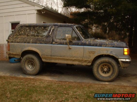 Mud-covered 1991 Ford Bronco parked next to a house