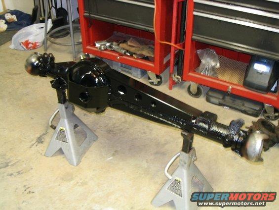 Black rear axle assembly on jack stands in a garage