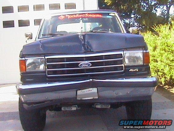Dark blue Ford Bronco with a dented hood and grille, seen from the front
