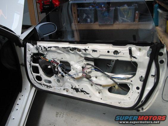 White car door interior with exposed wiring and components, viewed from the side