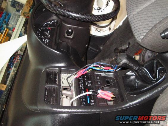 Car interior showing exposed wiring and audio connections near the gear shifter