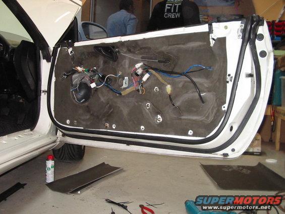 White car door interior with exposed wiring and insulation removed