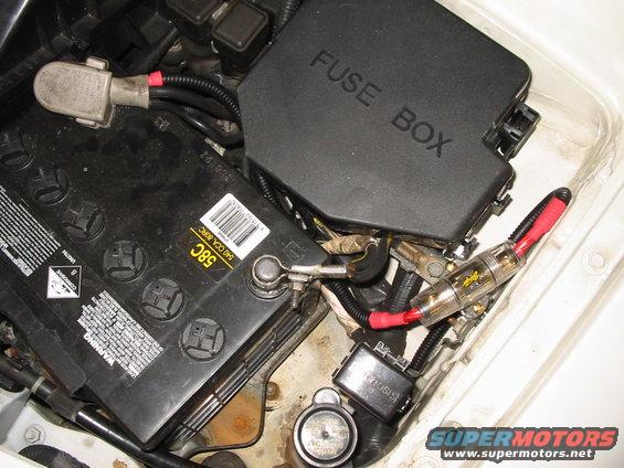 Car battery and fuse box with red-tipped fuse holder and wiring