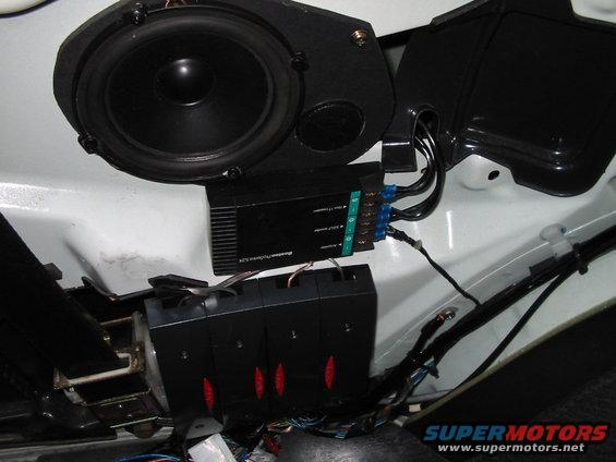 Car interior with speaker, amplifier, and wiring visible