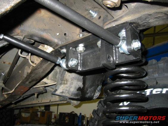 Aftermarket suspension components on a vehicle frame, with a coil spring and part of a tire visible
