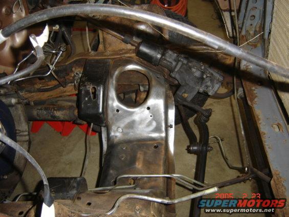 Vehicle frame with rusty metal, steering linkage, and brake lines visible