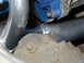 1968 Ford Mustang - A close-up view of exhaust headers and a blue engine mount, with visible bolts and metalwork.