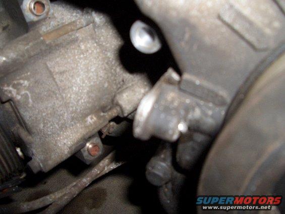 Close-up of a metal engine part with bolts and wires